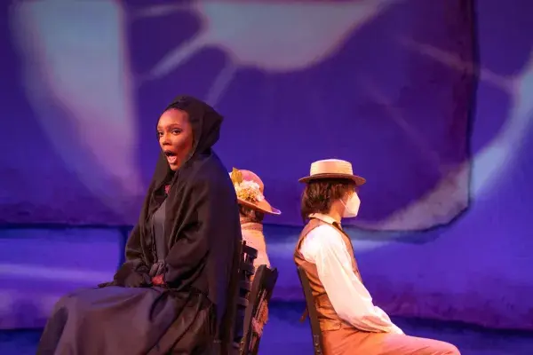 Image of Dejah Watts performing onstage in UK Opera Theatre's "Sanctuary Road" wearing a black dress of mourning