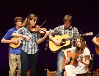 people playing guitars and fiddle on stage