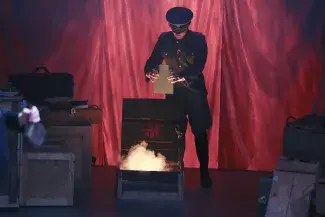 person in soldier costume putting paper in fire on stage
