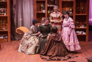 five women on stage in period dresses