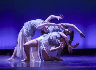 dancers on stage arched backwards with blue background light