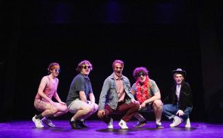 five actors kneeling on stage