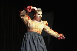 actor in yellow shirt on stage with arm outstretched
