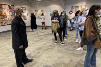Students browse the art gallery at the Lyric, some wearing face masks, while Whit Whitaker, wearing black suit and face mask, looks on