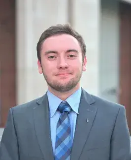 Headshot of Matthew Morse, wearing grey suit with blue shirt and tie