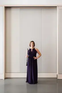 Image of ToniMarie Marchioni in black gown holding oboe against a white wall