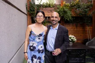 UK's Yuha Jung (left, wearing flowered sun dress) with Drexel University's Neville Vakharia (right, wearing grey suit and blue shirt), her coeditor, at the summer book launch party in Lexington. Photo by Mary Rollins Mathews, Rollins Studio.