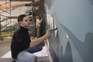 student painting on wall