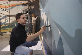 student painting on wall