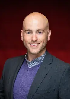 Nick Covault headshot on burgundy background
