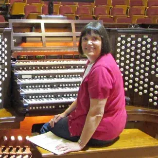 Jane Johnson looking at camera while sitting in front of a church organ
