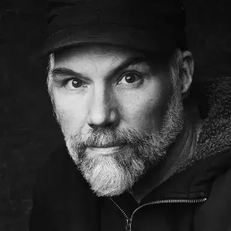 B/W headshot of Eric Stephenson wearing a dark zip up hoodie and dark cap
