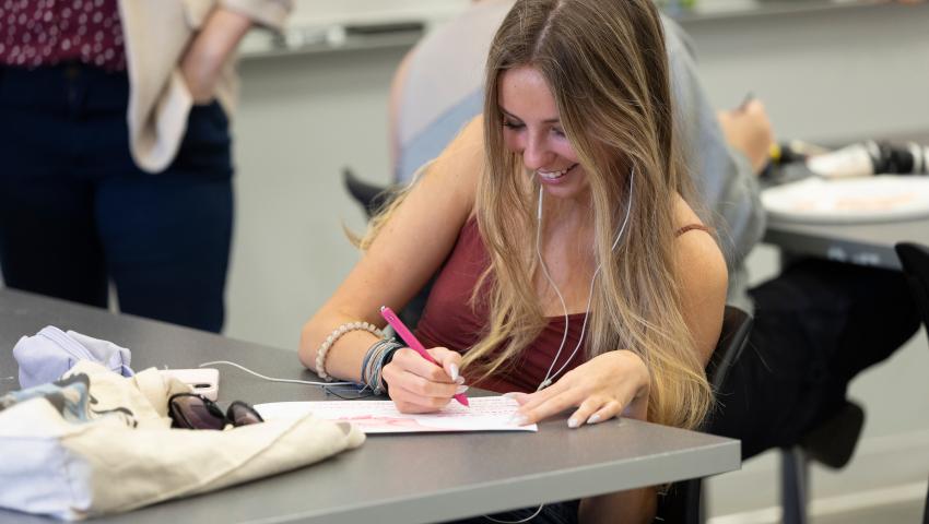 student writing on paper smiling