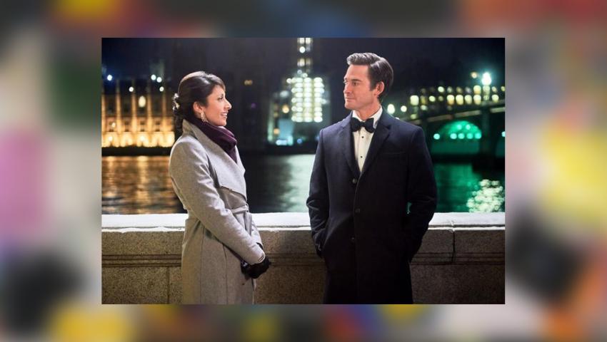 Screenshot of Countdown to Christmas movie, with woman in winter coat and man in tux on a bridge at night