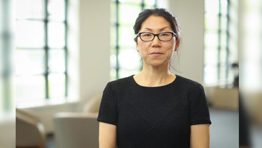 Image of Yuha Jung seated in front of bright windows wearing a black shirt and black glasses
