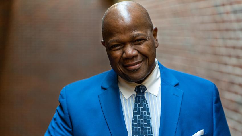 Headshot of Dr. Everett McCorvey wearing a blue suit against a brick wall backdrop