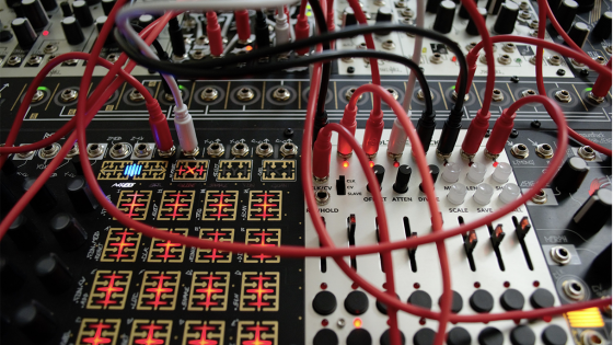 Close up on a professional mixer and soundboard with many red, white, and black crisscrossing wires.