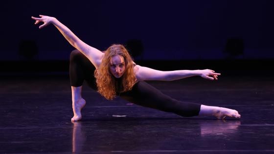 Student in deep lunge on stage looking at camera