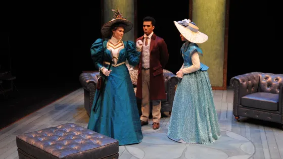 three actors on stage in period costumes