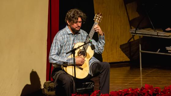 Image of Dieter Hennings Yeomans performing with guitar onstage at the Singletary Center during a performance of Collage in 2022.