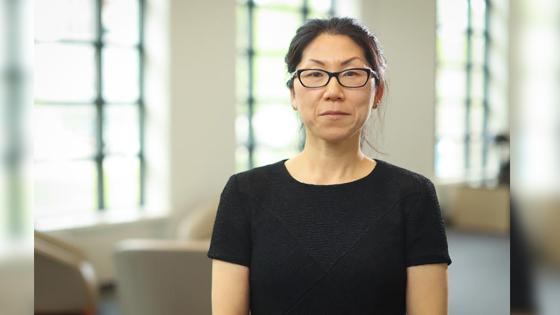 Image of Yuha Jung seated in front of bright windows wearing a black shirt and black glasses