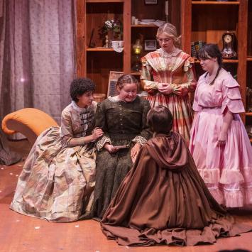 five women on stage in period dresses
