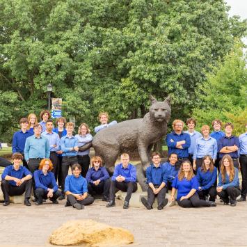 percussion students posed with statue of bowman the wildcat